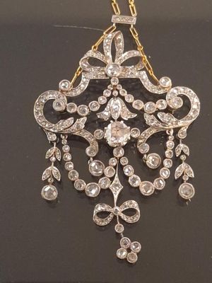 a close up of a diamond and gold necklace on a black surface
