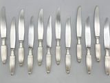six couteaux en métal argenté et six couteaux posés sur une table