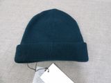 the beanie is green and has a tag attached to it