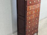 a tall chest of drawers in a room with a wall