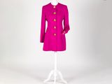 un manteau rose posé sur un pied de mannequin, devant un fond blanc