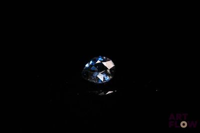 a close up of a blue diamond on a black surface