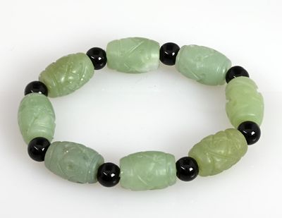 un bracelet vert orné de perles noires sur un fond blanc