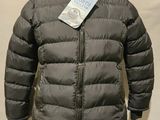 La veste est grise et possède une capuche doublée de fourrure.