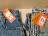 two pairs of jeans with tags on them sitting on a table