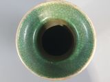 a green vase that is sitting on a white table
