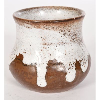 un vase brun et blanc posé sur une surface blanche