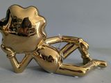 a gold figurine of a man laying on the ground