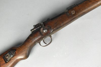an old rifle with a wooden handle on a white surface