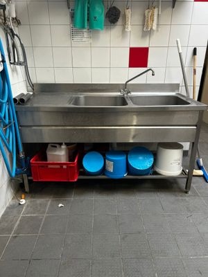 une cuisine équipée d'un évier en inox et d'un tuyau d'eau bleu