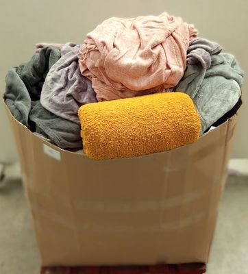 a bucket full of clothes and a towel on the floor