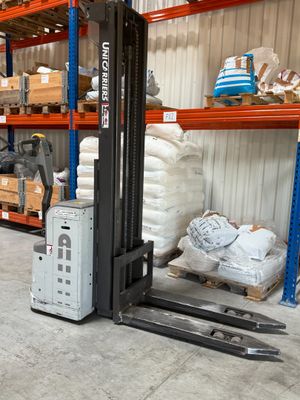 a forklift in a warehouse with a lot of boxes on the shelves
