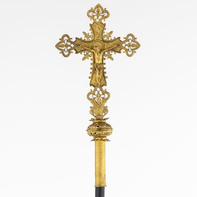 a gold cross on a black stand with a white background