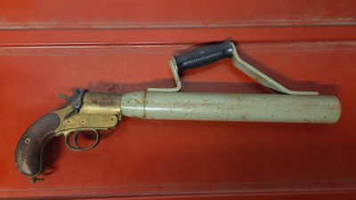 un vieux pistolet exposé dans une vitrine, posé sur un socle rouge