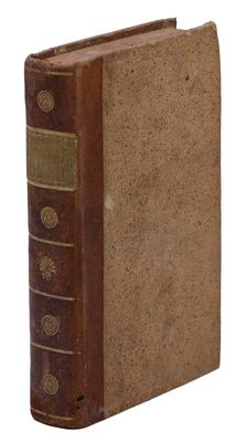 un vieux livre à la couverture brune posé sur une surface blanche
