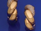 une paire de boucles d'oreilles en or jaune et diamants sur un fond bleu