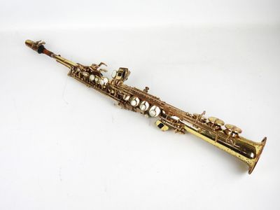 un gros plan d'un saxophone posé sur une surface blanche, avec un fond blanc