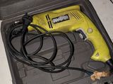 a yellow corded drill sitting in a tool box