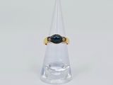 un gros plan d'une bague ornée d'une pierre noire posée au sommet d'un cône transparent