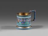 une tasse bleue et dorée avec une anse, posée sur une surface grise
