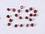a group of red garnets sitting on top of a white surface
