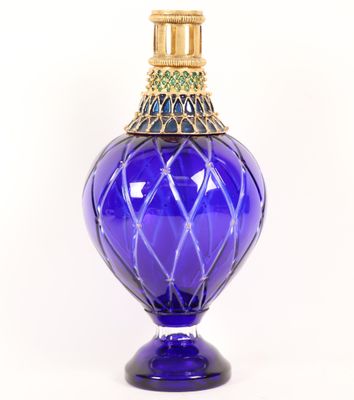 un vase en verre bleu orné d'un couvercle doré, sur fond blanc