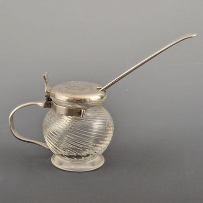 une cafetière ancienne en métal argenté, accompagnée d'une cuillère en forme de pot à miel
