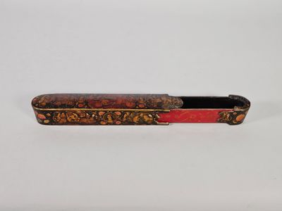 une image représentant un stylo rouge et doré avec un manche noir