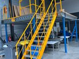 a yellow staircase in a warehouse next to some tables and chairs