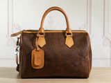 the brown and tan handbag is sitting on a wooden table