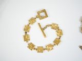 a picture of a gold bracelet with a clock in the middle of it