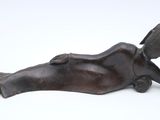 bronze statue of a woman laying on her back on a white surface