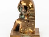 bronze statue of a man with a gold helmet on a wooden base
