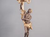 statue d'un homme tenant un lustre, posée sur un socle en marbre