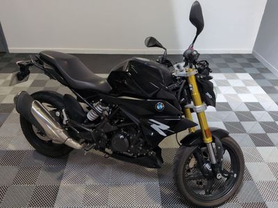 une photo d'une moto noire garée sur un sol à damier