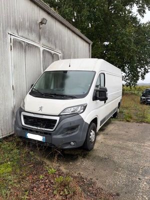 La camionnette blanche est garée devant un immeuble, à côté d'un arbre.