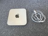 an apple mac mini computer sitting on top of a carpet next to a pair of ear buds