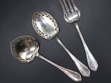 three silver spoons and a fork on a black surface