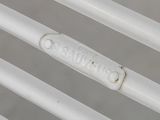 a close up of a white metal bench with a name plate on it