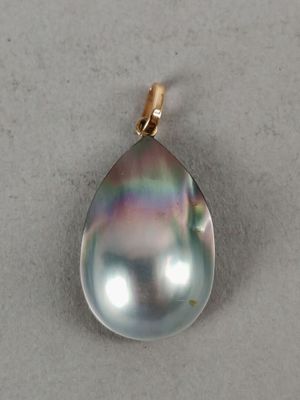 a close up of a black pearl pendant on a white surface