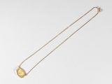 gros plan d'un collier en or sur une surface blanche