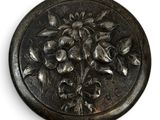 a metal button with flowers on it on a white surface