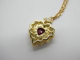 un collier en or orné d'une pierre rouge au centre