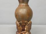 un vase en bronze posé sur une table, sur lequel sont représentés deux oiseaux