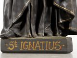 a statue of st ignatiuso holding a cross on top of a book