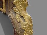 a gold and red clock with a man ' s face on it