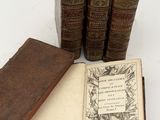 several old books sitting on top of each other on a white surface