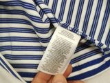 someone is holding a white and blue striped shirt that has a tag on it