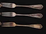 four forks and two spoons on a black table