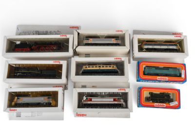tout un tas de trains miniatures différents, rangés dans des boîtes sur la table